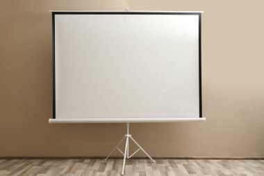 Bej duvarın yakınındaki boş projeksiyon ekranı. Desenleme için boşluk