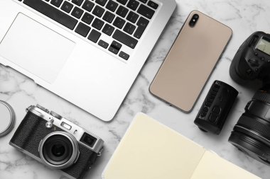 Düz kompozisyon dizüstü bilgisayarı, kameraları ve akıllı telefonu beyaz mermer masanın üzerinde yatıyordu. Tasarımcının işyeri