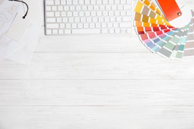 Klavye ve palet örnekleriyle bembeyaz ahşap masa üzerinde düz kompozisyon, yazı için boşluk. Tasarımcının işyeri