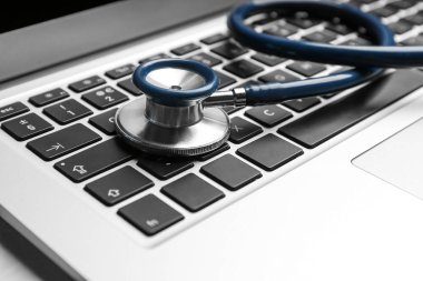 Laptop ve steteskop masada, yakın plan. Teknik destek kavramı