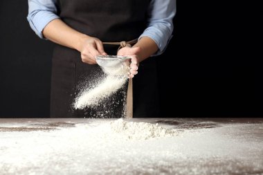 Masada buğday unu karıştıran kadın siyah arka planda, yakın plan