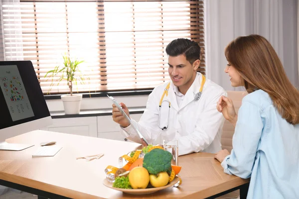 Διατροφολόγος σύμβουλος ασθενή στο τραπέζι στην κλινική — Φωτογραφία Αρχείου
