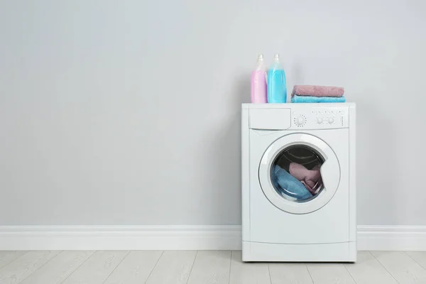 Modern washing machine with stack of towels and detergents near — 스톡 사진