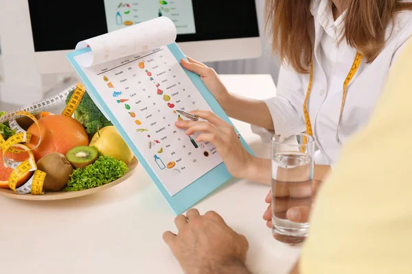 Young nutritionist consulting patient at table in clinic, closeu — Stock Photo, Image