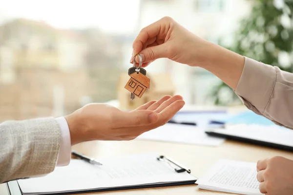 Real estate agent giving key with trinket to client in office, c — 스톡 사진