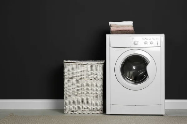 Modern washing machine and laundry basket near black wall — 스톡 사진