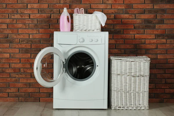 Máquina de lavar roupa moderna com detergente e cestas de roupa perto b — Fotografia de Stock