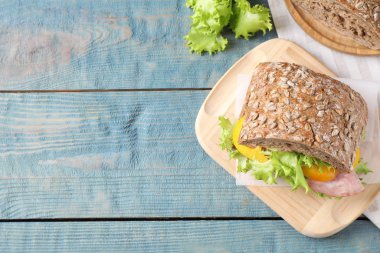 Açık mavi ahşap masada jambonlu lezzetli bir sandviç. Metin için boşluk