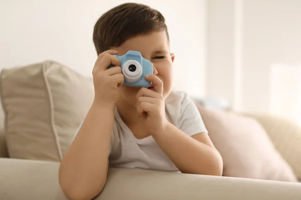 Liten fotograf tar bild med leksak kamera på soffan hos ho — Stockfoto