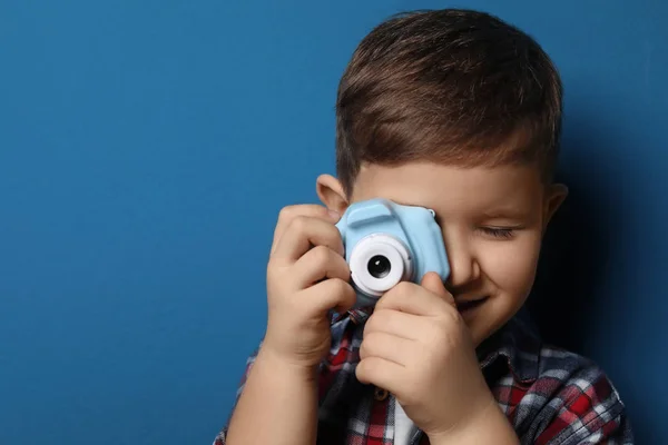 Little photographer taking picture with toy camera on blue backg — Stockfoto