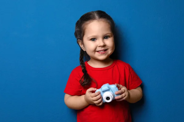 Kleiner Fotograf mit Spielzeugkamera auf blauem Hintergrund — Stockfoto