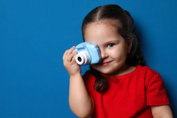 Pequeño fotógrafo tomando fotos con cámara de juguete en respaldo azul —  Fotos de Stock