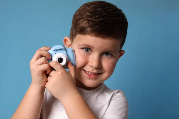 Kleine fotograaf met speelgoedcamera op lichtblauwe achtergrond — Stockfoto