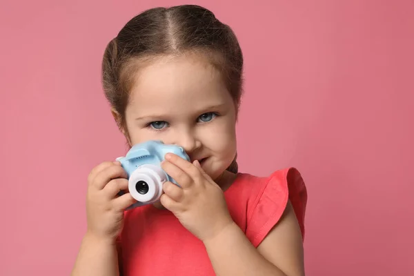 Маленький фотограф с игрушечной камерой на розовом фоне — стоковое фото