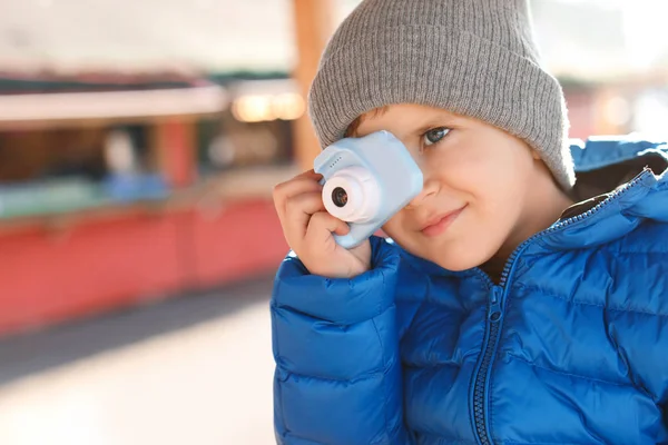 Маленький фотограф фотографирует с игрушечной камерой на улице — стоковое фото