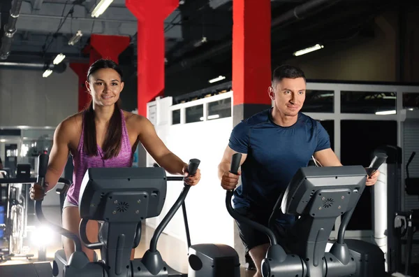 Couple working out on elliptical trainers in gym — 图库照片