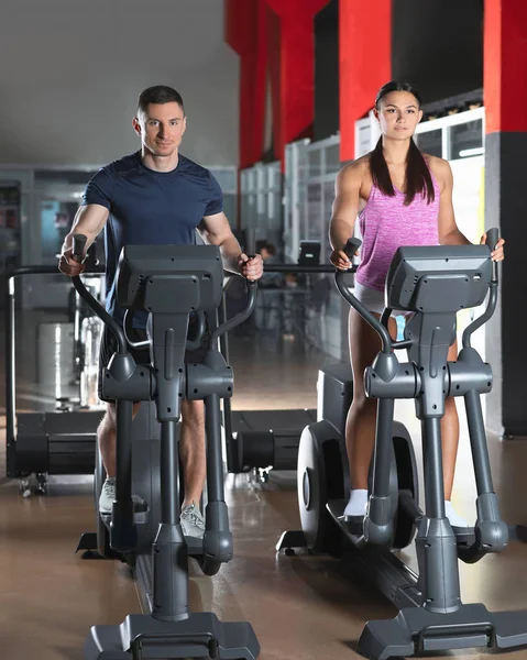 Couple working out on elliptical trainers in gym — Stok fotoğraf