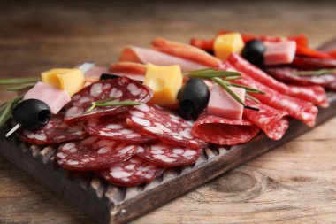 Tasty ham with other delicacies served on wooden table, closeup