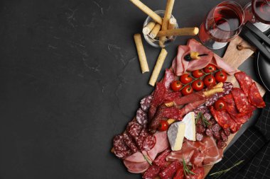 Tasty ham with other delicacies served on black table, flat lay. Space for text