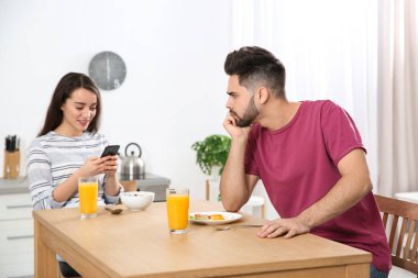 Evde akıllı telefonu erkek arkadaşına tercih eden genç bir kadın.