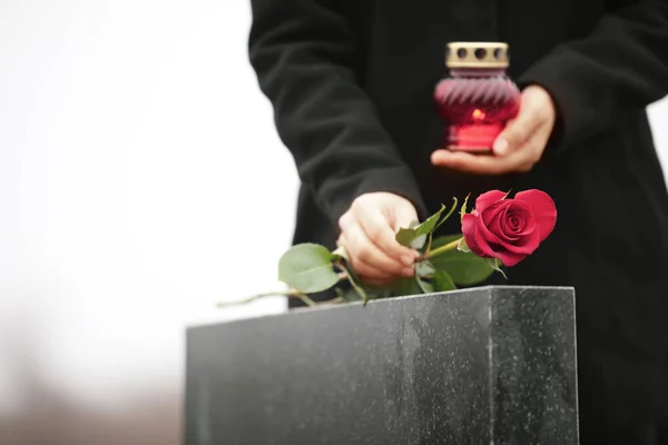 Žena se svíčkou v blízkosti černé žulové náhrobní kámen venku, zaměření o — Stock fotografie