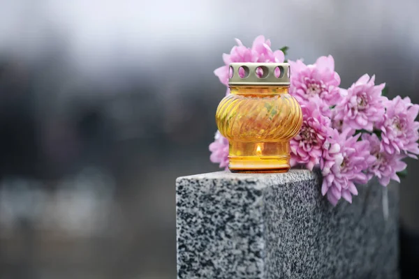 Chryzantéma květiny a svíčka na šedé žulové náhrobní kámen outdo — Stock fotografie