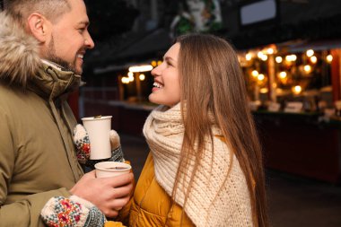 Happy couple with mulled wine at winter fair