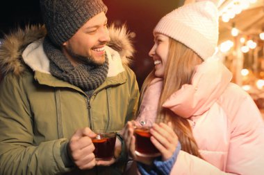 Happy couple with mulled wine at winter fair
