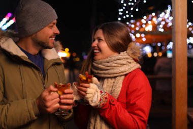 Happy couple with mulled wine at winter fair
