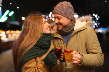 Happy couple with mulled wine at winter fair