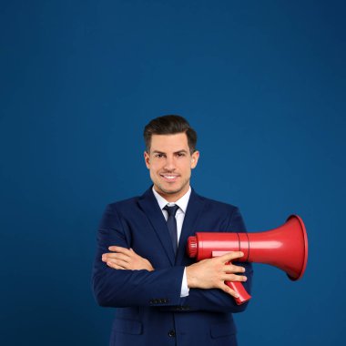 Mavi arka planda megafonu olan yakışıklı bir adam.