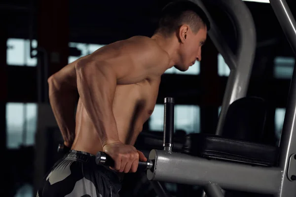 Silny mężczyzna ćwiczący na równoległych barach w nowoczesnej siłowni — Zdjęcie stockowe