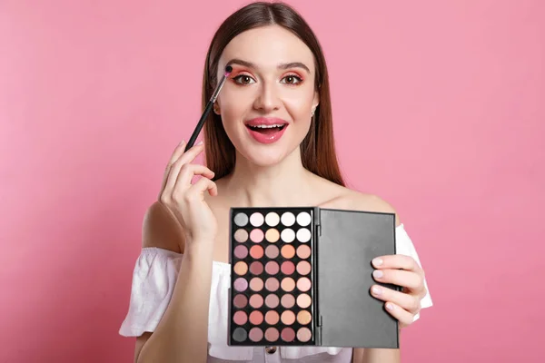 Beauty blogger applying eyeshadow on pink background — Stock Photo, Image