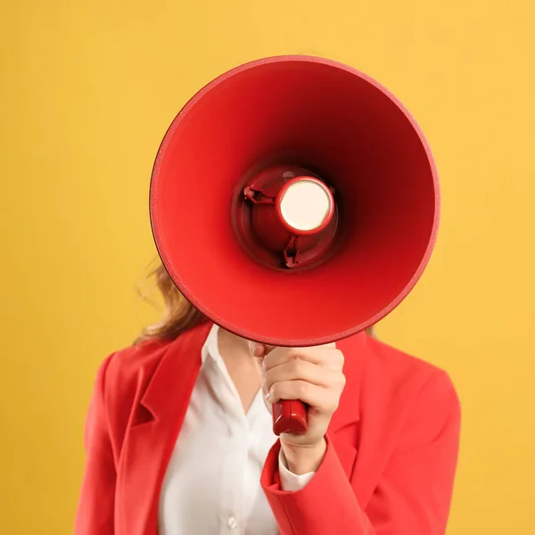 Jovem mulher com megafone no fundo amarelo — Fotografia de Stock