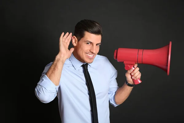 Hombre guapo con megáfono sobre fondo negro — Foto de Stock