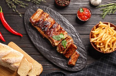 Delicious grilled ribs served on black wooden table, flat lay clipart