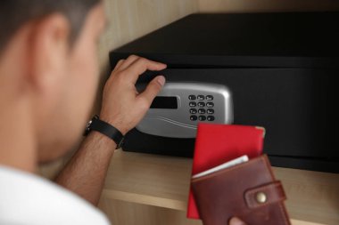 Otelde elektronik kilitle siyah çelik kasa açan adam, yakın plan.