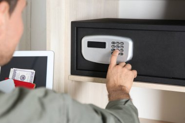 Otelde elektronik kilitle siyah çelik kasa açan adam, yakın plan.
