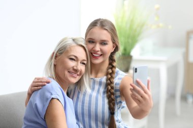Mutlu anne ve kız evde selfie çekiyorlar.