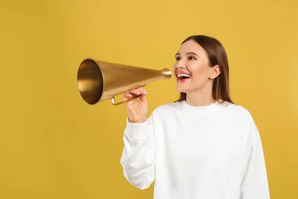 Mladá žena s vintage megaphone na žlutém pozadí — Stock fotografie