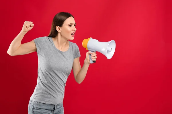 Jovem mulher com megafone no fundo vermelho — Fotografia de Stock