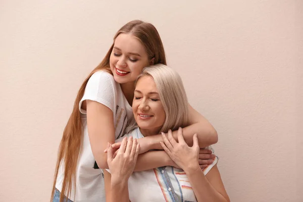 Mother and her adult daughter on beige background — Stock Photo, Image