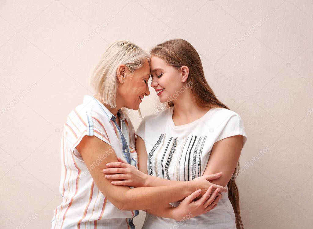 Mother and her adult daughter on beige background