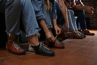 Arkadaşlar bovling kulübünde ayakkabı giyer, bacaklara yakın çekim yapar.