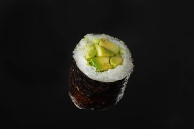 Siyah arka planda avokadolu suşi rulosu.