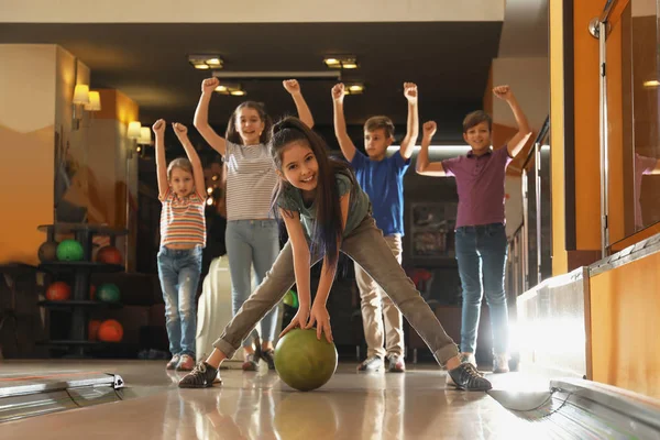 Girl throwing ball and spending time with friends in bowling club