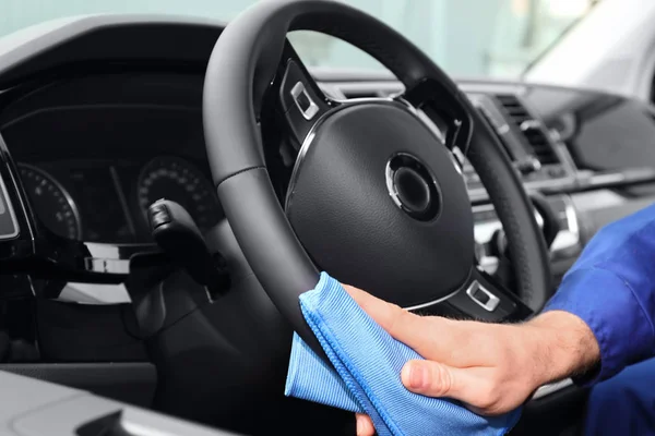 Car wash worker cleaning automobile interior, closeup