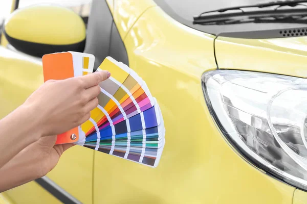 Femme avec des échantillons de palette en choisissant la couleur pour la peinture de voiture, clos — Photo