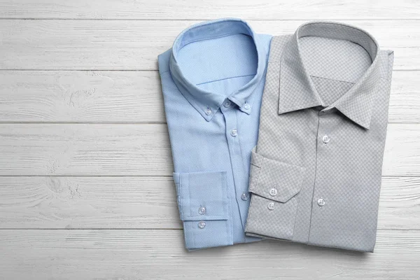 Camisas masculinas con estilo sobre fondo de madera blanca, planas. Espacio —  Fotos de Stock