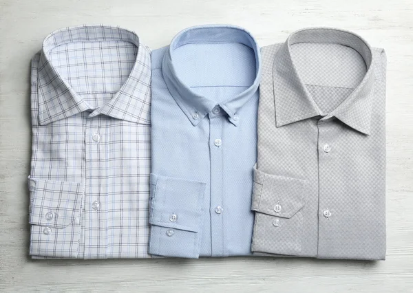 Camisas masculinas con estilo sobre fondo blanco de madera, planas — Foto de Stock